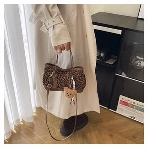 Detail of leopard print handbag with brown leather handles and cute bear charm accent