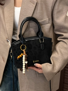 Chic black leopard texture handbag with gold hardware and beaded strap charm