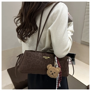 Detail of leopard print underarm bag with plush bear charm and striped scarf detail