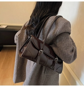 Detailed view of glossy dark brown patent leather shoulder bag with silver buckles