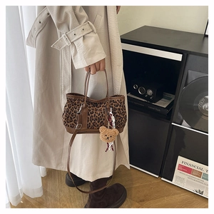 Detail of leopard print bucket bag with leather handles and cute bear charm accessory