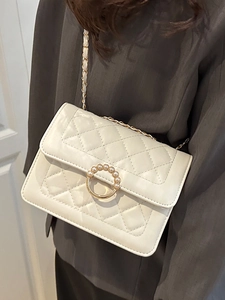 White quilted crossbody bag with pearl buckle and metal chain strap shown on model