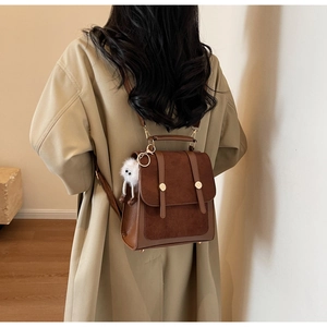 Detail of vintage-style backpack with brown suede texture and plush monster charm
