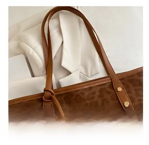 Detail of leopard print tote bag featuring brown leather handle and gold rivet hardware