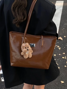 French vintage brown patent leather tote bag with plush bear charm in autumn street setting