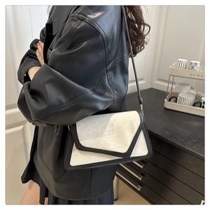 Detail of black and white leather crossbody bag with textured fur flap on a model