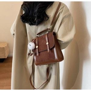 Detailed back view of vintage brown patchwork leather backpack with plush pendant