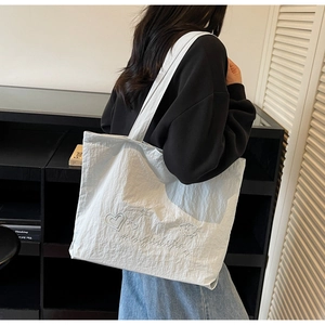 Detail of white tote bag with elegant floral and heart embroidery on light nylon fabric