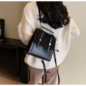 Detail of black dual-use backpack with gold buckle and plush charm on female model