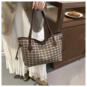 Detail of vintage plaid tote bag with brown leather handles and side drawstring accent