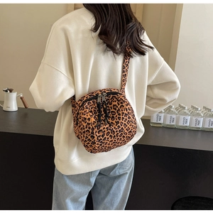 Detail view of leopard print crossbody bag featuring double zippers and canvas material