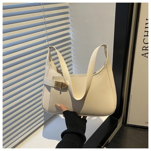 Detail view of the sleek metal buckle and side strap on this cream underarm handbag