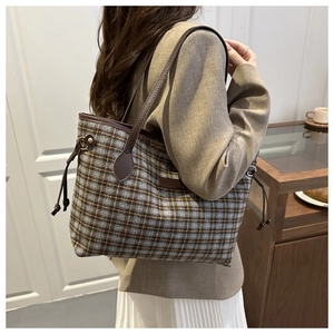 Close-up of blue and yellow plaid tote bag with brown leather straps and drawstring detail