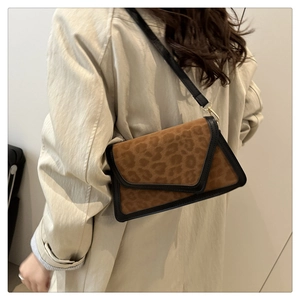 Detail of leopard print crossbody bag with black piping on beige trench coat outfit