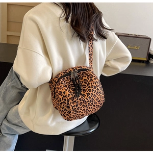 Detail of leopard print crossbody canvas bag showing dual zippers and woven shoulder strap