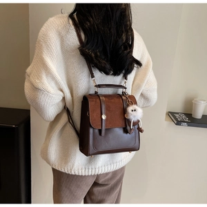 Detail of faux leather backpack showing brown patchwork texture and plush charm