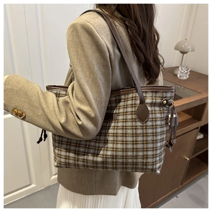 Detail of checkered tote bag in grey and yellow wool with brown leather straps on model