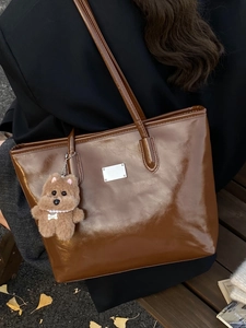 French vintage dark brown glossy tote bag with dog pendant on a wooden bench