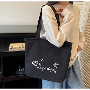 Detail view of black canvas tote bag with white artistic heart and sheep illustrations