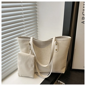Detailed view of the ivory tote bag set with matching pouch and gold rivet accents