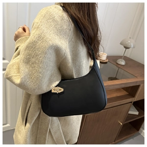 Detail of a black matte leather underarm bag with a vintage gold twist lock on the shoulder