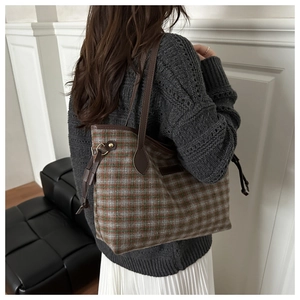 Detail of checkered tote bag with brown leather straps shown on model in modern setting