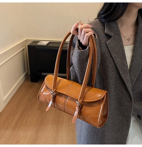 Detail of vintage brown baguette bag with vertical stitching and metal buckle accents