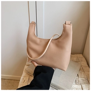 Detail of beige crescent shoulder bag showing high-quality lychee texture and modern design