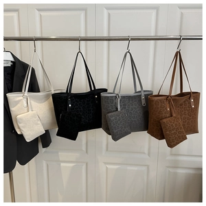 Detail view of leopard print tote bags in four colors with matching pouches on a door
