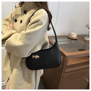 Detail of a minimalist black leather underarm bag with gold metal buckle on a beige coat