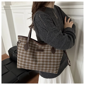 Fashionable checkered tote bag in brown and green wool worn over the shoulder by a model