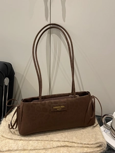 Brown faux suede underarm bag with bow drawstring details and adjustable shoulder strap