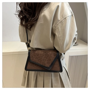 Detail of leopard print crossbody bag with black leather trim and envelope flap closure
