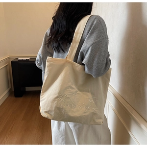 Detail of cream canvas tote bag featuring delicate star and heart embroidery on fabric