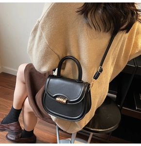 Classic black saddle bag with golden clasp worn over a brown autumn sweater style