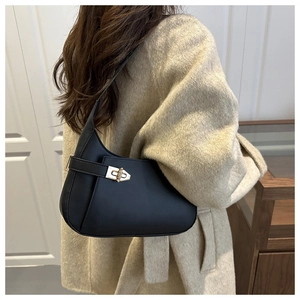 Detail of minimalist black crescent shoulder bag with a gold twist-lock on a beige coat