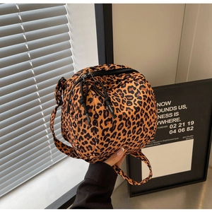 Macro detail of round leopard print canvas crossbody bag featuring a black double zipper