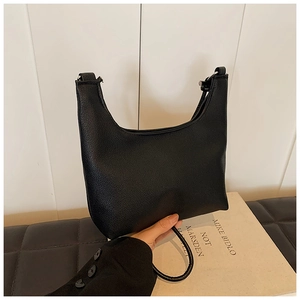 Close-up of black litchi-textured leather shoulder bag with minimalist curved design