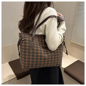 Detailed view of checkered tote bag with brown leather straps worn by a model
