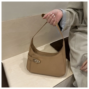 Detailed view of camel faux leather underarm bag with decorative gold twist lock buckle