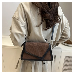 Brown leopard print suede crossbody bag styled with a beige trench coat on a model