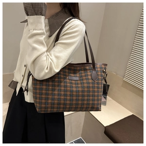 Detail of checkered woven tote bag with brown leather handles and side drawstring accents