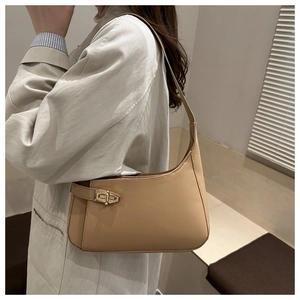 Side view of woman wearing a light brown leather shoulder bag with gold metal buckle
