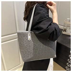 Close-up of leopard print tote bag with grey leather handles and gold rivet accents