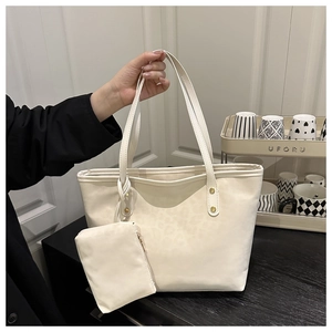 Close-up of minimalist cream tote bag with matching mini pouch and gold hardware