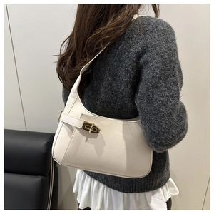 Close-up of a cream white leather hobo bag with gold buckle on a model's shoulder