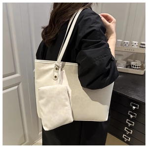 Minimalist beige tote bag with a matching small zipper pouch shown in use by a model