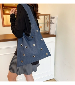 Détail d'un sac cabas en denim bleu avec œillets dorés et large bandoulière
