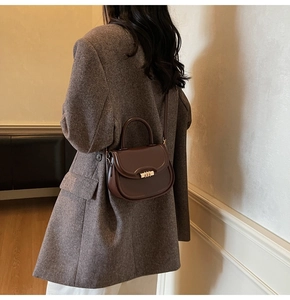 Detail of a dark brown vintage saddle bag worn with a wool blazer for a chic look