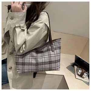Close-up of stylish plaid tote bag in grey and brown with premium leather handles